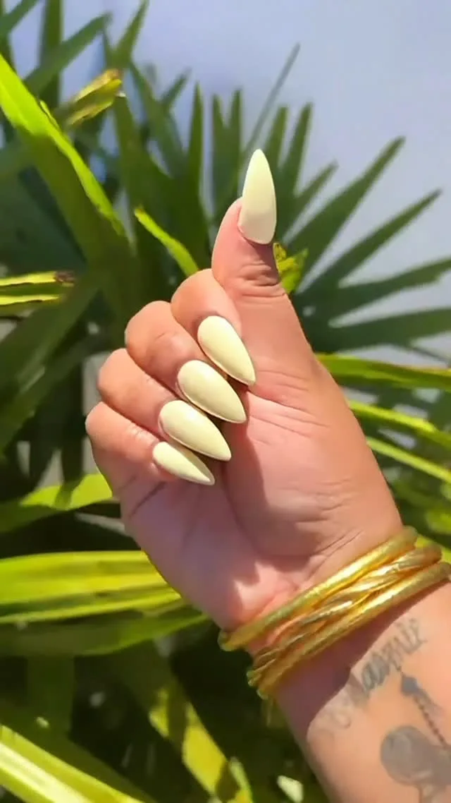 Ongles stiletto jaune beurre en extérieur sous le soleil